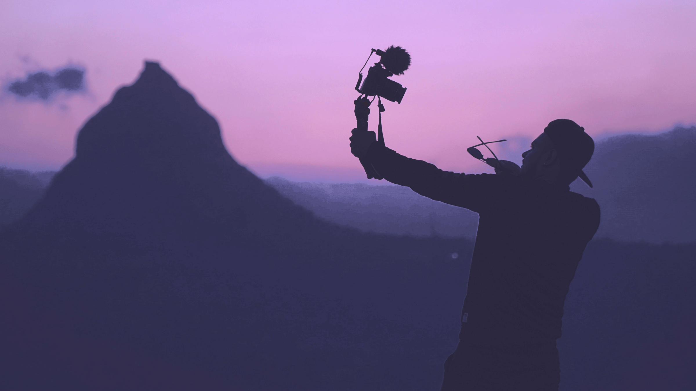Man vlogging himself with a large camera in the outdoors of a desert