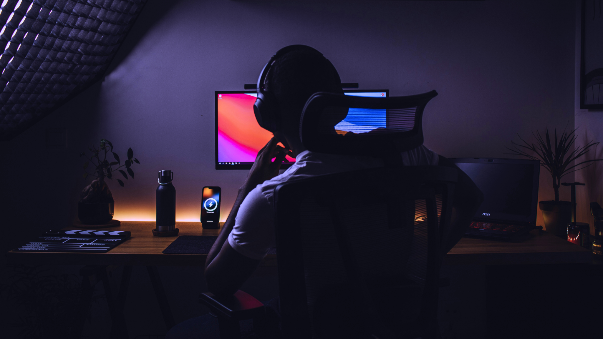 A rear shot of a person sitting in front of a dual monitor computer setup